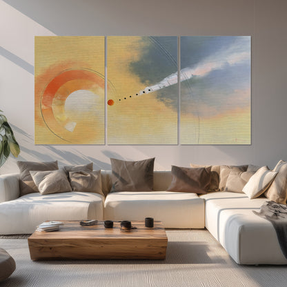 A warm orange circular form and diagonal pale streaks across a muted yellow and blue field set of 3 poster prints displayed in a living room