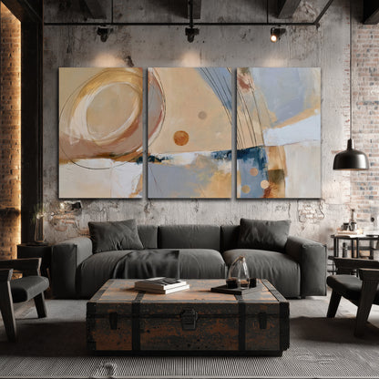 Pale circular forms and fine diagonal lines layered over blue, peach and cream brushstrokes 3 piece canvas wall art displayed in a industrial room