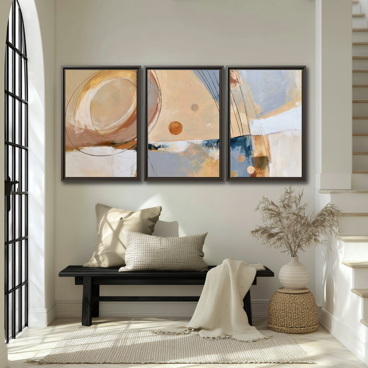 Pale circular forms and fine diagonal lines layered over blue, peach and cream brushstrokes 3 piece framed canvas wall art displayed in a entryway