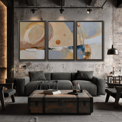 Pale circular forms and fine diagonal lines layered over blue, peach and cream brushstrokes 3 piece framed canvas wall art displayed in a industrial room