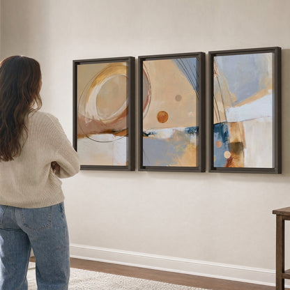 Pale circular forms and fine diagonal lines layered over blue, peach and cream brushstrokes 3 piece framed canvas wall art three panel arrangement on a wall
