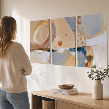 Pale circular forms and fine diagonal lines layered over blue, peach and cream brushstrokes set of 3 poster prints three panel arrangement on a wall