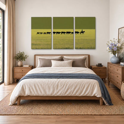 A rider leading a long line of cattle across a wide green and golden plain 3 piece canvas wall art styled in an interior