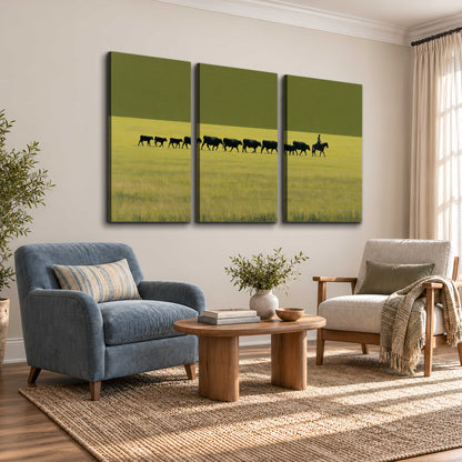 A rider leading a long line of cattle across a wide green and golden plain 3 piece canvas wall art styled in an interior