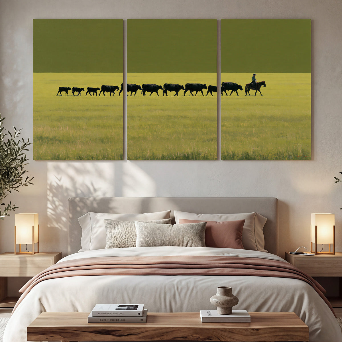 A rider leading a long line of cattle across a wide green and golden plain 3 piece canvas wall art displayed in a bedroom