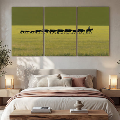 A rider leading a long line of cattle across a wide green and golden plain 3 piece canvas wall art displayed in a bedroom