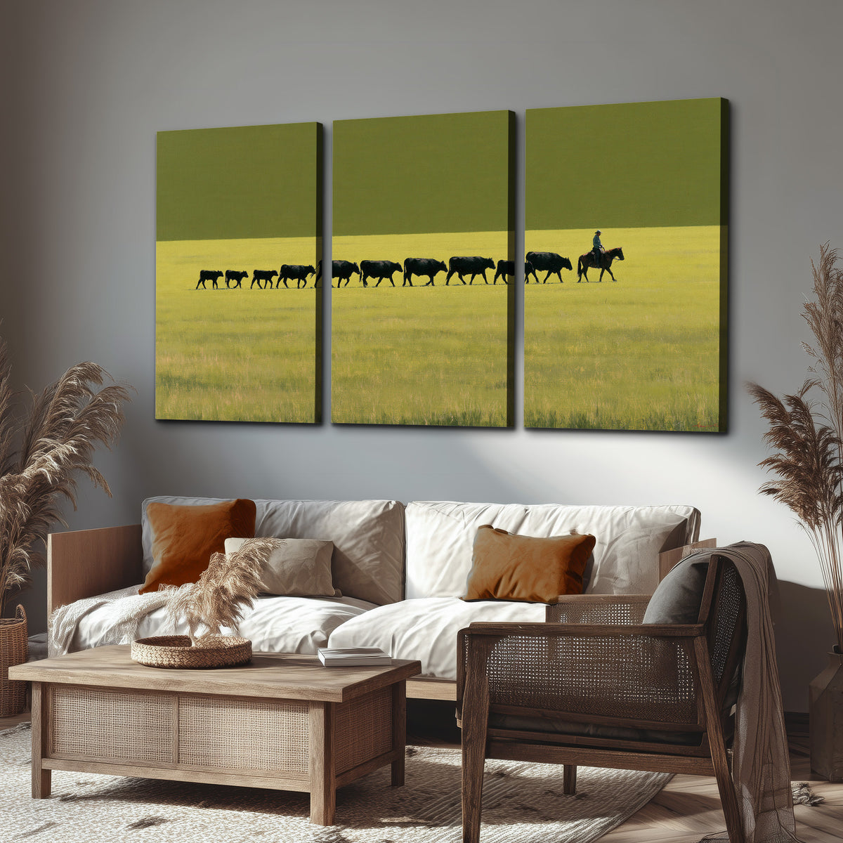 A rider leading a long line of cattle across a wide green and golden plain 3 piece canvas wall art displayed in a rustic living room