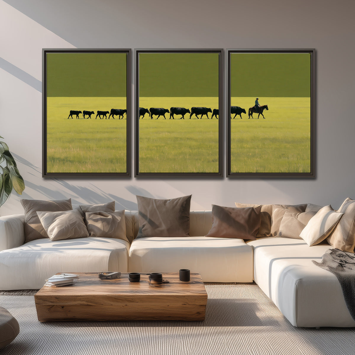 A rider leading a long line of cattle across a wide green and golden plain 3 piece framed canvas wall art displayed in a living room