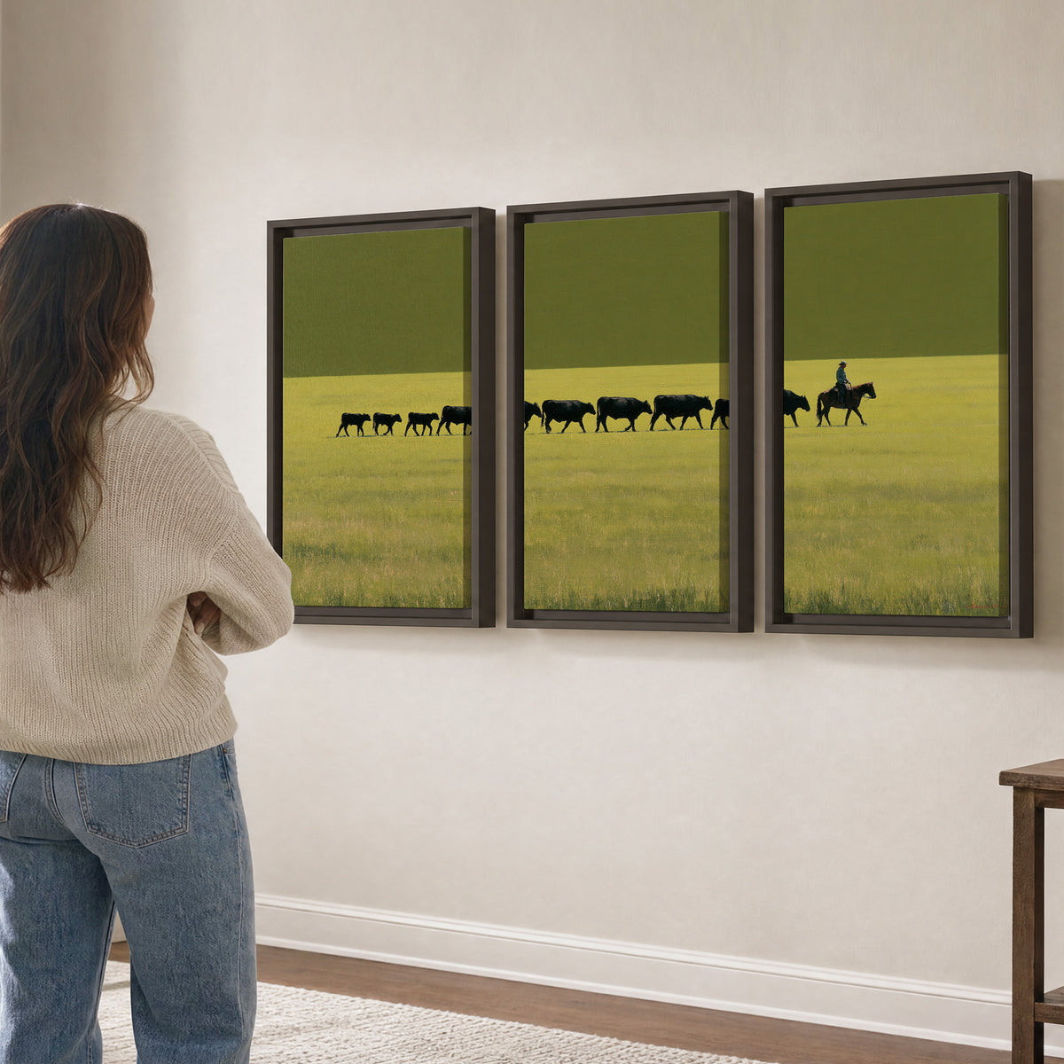 A rider leading a long line of cattle across a wide green and golden plain 3 piece framed canvas wall art three panel arrangement on a wall