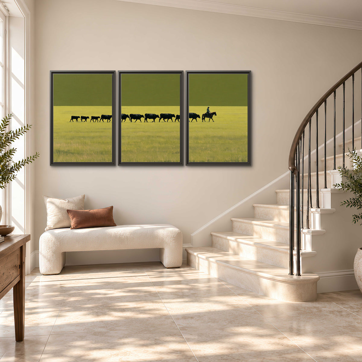 A rider leading a long line of cattle across a wide green and golden plain 3 piece framed canvas wall art styled in an interior