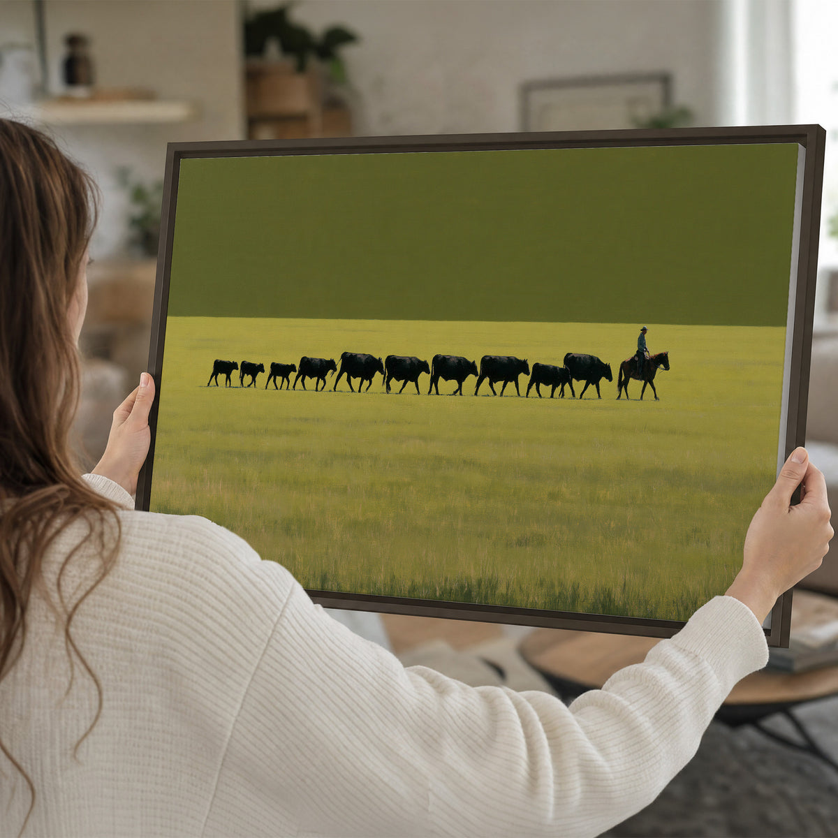 A rider leading a long line of cattle across a wide green and golden plain single framed canvas wall art held in hands