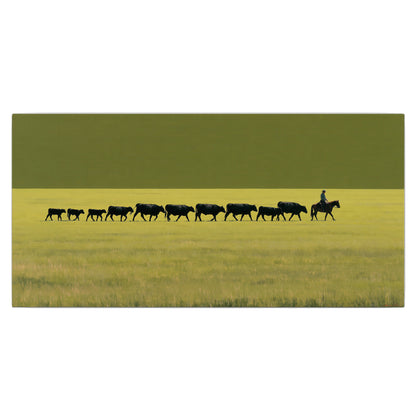 A rider leading a long line of cattle across a wide green and golden plain single canvas wall art viewed straight on