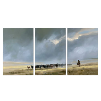 A rider and cattle moving across a sunlit grassland beneath a dramatic blue-gray sky 3 piece canvas wall art viewed straight on