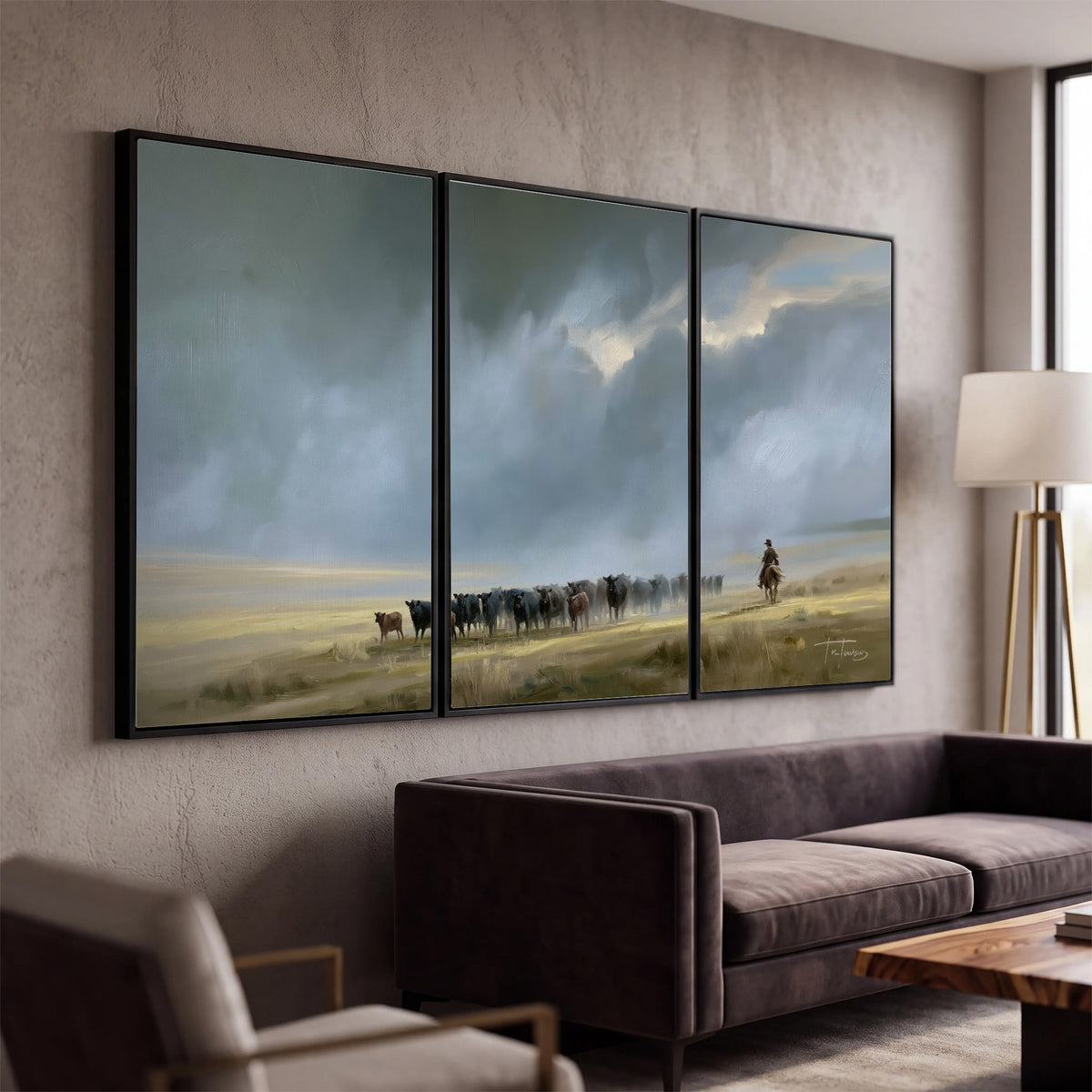 A rider and cattle moving across a sunlit grassland beneath a dramatic blue-gray sky 3 piece framed canvas wall art displayed in a modern living room