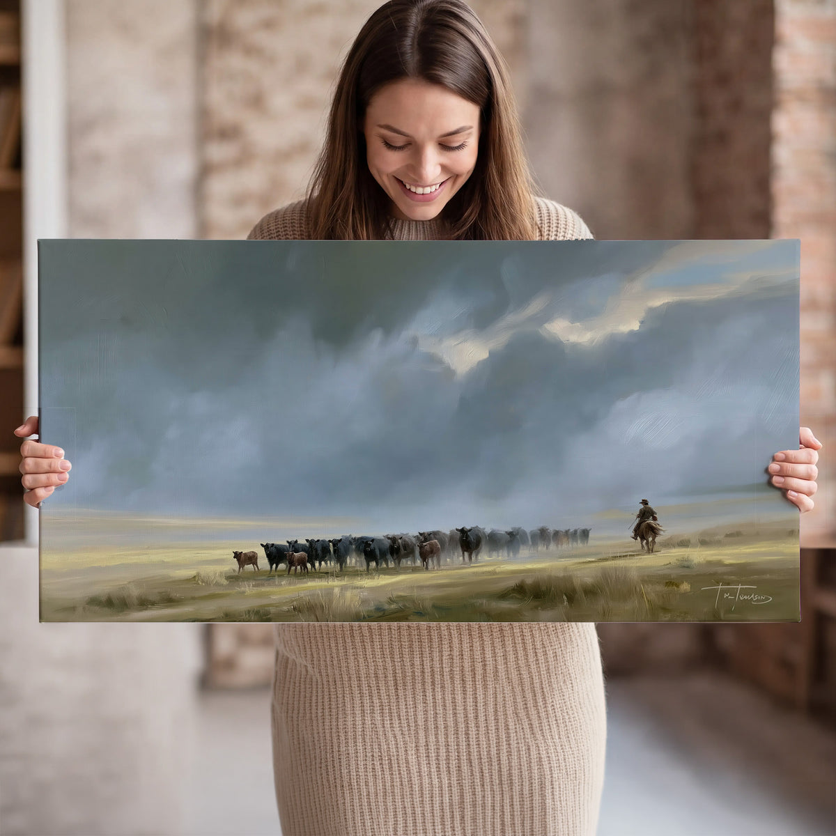 A rider and cattle moving across a sunlit grassland beneath a dramatic blue-gray sky single canvas wall art held in hands