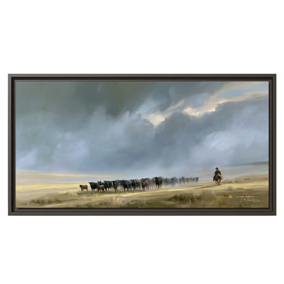 A rider and cattle moving across a sunlit grassland beneath a dramatic blue-gray sky single framed canvas wall art viewed straight on
