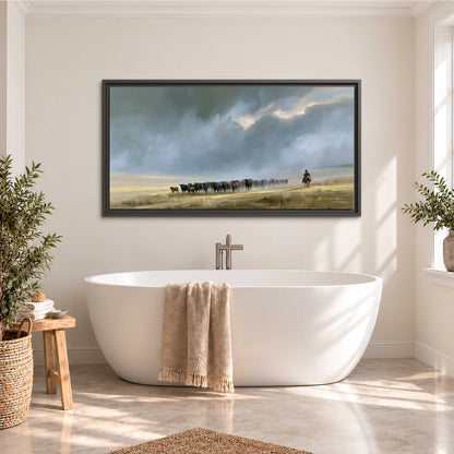 A rider and cattle moving across a sunlit grassland beneath a dramatic blue-gray sky single framed canvas wall art styled in an interior