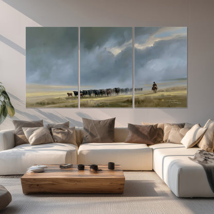 A rider and cattle moving across a sunlit grassland beneath a dramatic blue-gray sky set of 3 poster prints displayed in a living room